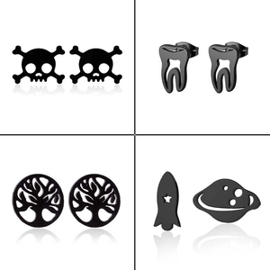 Macro detail of black stainless steel earrings featuring skull, tree and planet designs
