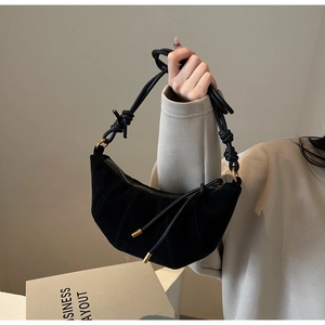Detail of black suede crescent bag with decorative stitching and knotted handle