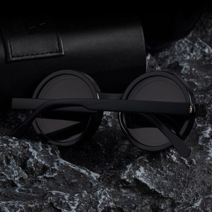 Detail of round black polarized sunglasses on volcanic rock with a leather case