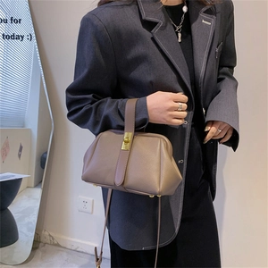 Retro brown lychee leather handbag with golden lock worn by a woman in a blazer