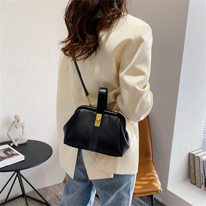 Retro black litchi pattern leather shell bag with gold clasp shown on model shoulder
