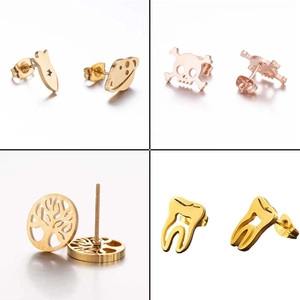 Set of four asymmetric gold ear studs featuring rocket, skull, tree of life, and tooth designs