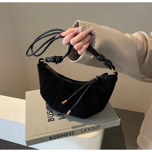 Detail of black matte crescent bag with gold metal accents and slim shoulder strap