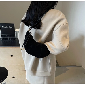 Detail of black crescent moon bag with matte finish and gold cylindrical metal fasteners