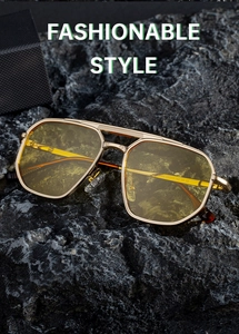 Detail of square gold metal aviator sunglasses with yellow lenses on a dark stone background