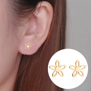 Boucles d'oreilles fleur évidée dorée minimaliste portées avec vue détaillée en gros plan