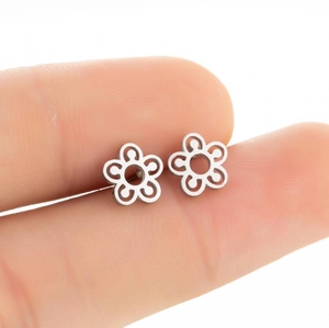 Gros plan de boucles d'oreilles fleurs en acier inoxydable argenté tenues à la main