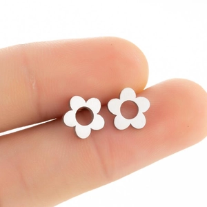 Gros plan sur la boucle d'oreille fleur minimaliste en acier argenté à la main