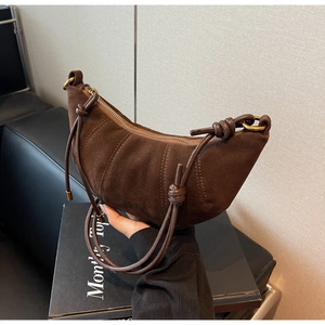 Detail of matte suede croissant bag with knotted strap and metal zipper closure