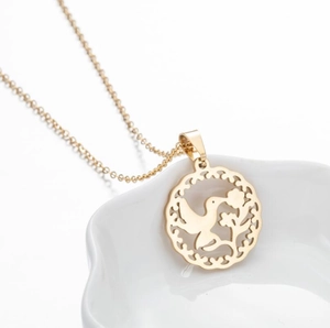 Detailed close-up of a gold hollow pendant with bird and floral patterns on an O-chain