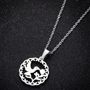 Macro detail of silver geometric hummingbird pendant on starry black background