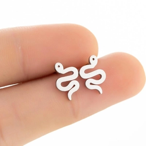 Macro view of polished silver snake-shaped stud earrings held between fingertips