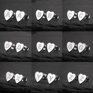 Detail view of heart-shaped stainless steel stud earrings with brushed metal letters