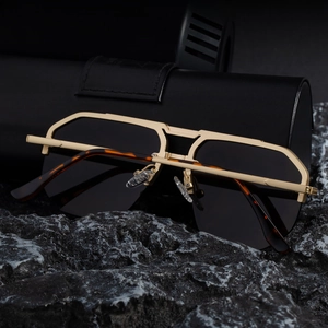 Detail of pilot sunglasses with gold metal double bridge on a stone texture base