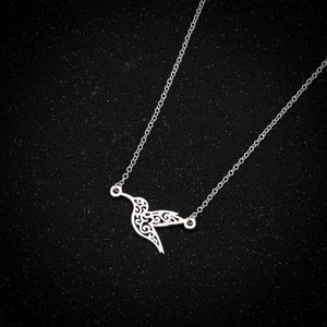 Macro shot of silver hummingbird pendant with hollow-out pattern on black star background