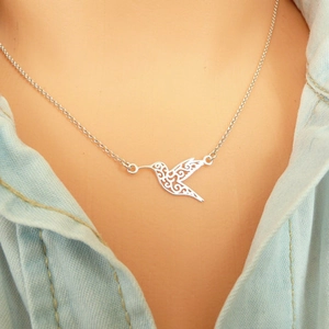 Minimalist stainless steel hummingbird necklace with hollow origami bird pendant on a model