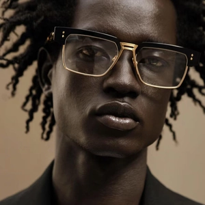 Detail of retro rectangular sunglasses with black frame and gold metal accents on a model