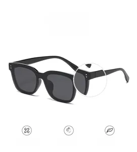 Détail de lunettes de soleil carrées noires avec rivets argentés et charnière en métal robuste