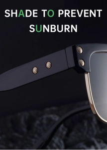 Detail of half-frame sunglasses featuring silver rivets and gold metal trim on black frame