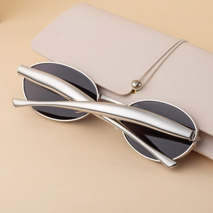 Detail view of silver oval sunglasses with unique sculptural temples and dark lenses