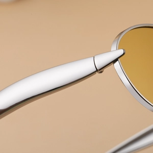 Detail of silver metal frame hinge and yellow transparent lens on fashion sunglasses