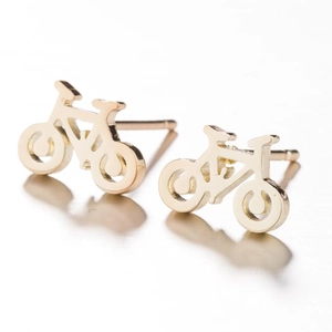 Macro de boucles d'oreilles vélo dorées montrant les détails de la roue et du cadre