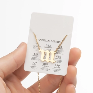Détail du pendentif lettre m gothique dorée avec carte de chiffres des anges