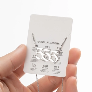 Détail du pendentif nombre d'ange 555 argenté sur carte de signification symbolique