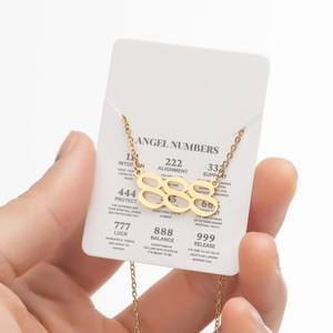 Gros plan du collier pendentif chiffre ange 888 doré sur carte d'information
