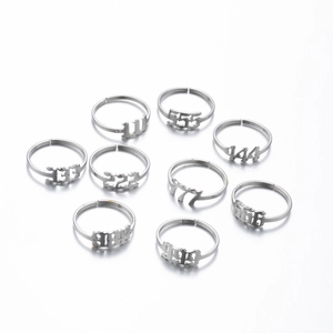 Flat lay of 9 silver angel number rings with cutout digits 111-999 and adjustable bands