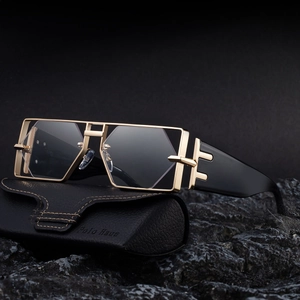 Quadratische Metall-Sonnenbrille mit Goldrahmen und grauen Gläsern auf schwarzem Etui