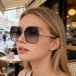 Detail of gradient grey lenses and golden metal temples with H pattern on sunglasses