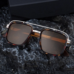Polarized double-bridge square sunglasses with tortoiseshell frames on a dark rock