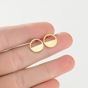 Macro shot of gold-plated geometric semicircular studs held by hand for size reference