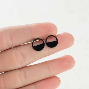 Macro view of geometric semi-circle stud earrings in matte black finish on fingers
