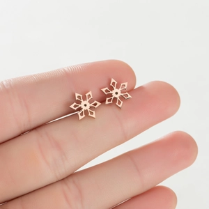 Close-up of rose gold snowflake stud earrings with hollow design held on a fingertip
