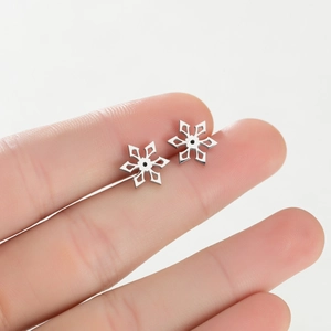 Close-up of small silver snowflake stud earring shown on a finger for size reference