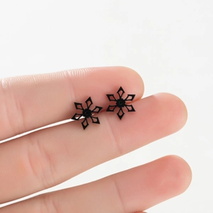 Detailed view of black snowflake earrings in hand showing the 18K gold plated design