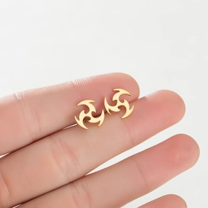 Détail macro de boucles d'oreilles en acier doré avec design de symbole tourbillon poli
