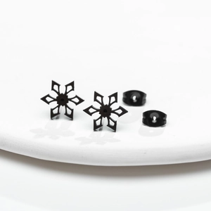 Matte black snowflake stud earrings in stainless steel on a white minimalist plate