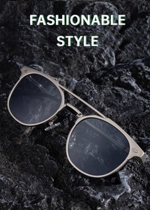 Detail of men's metal aviator sunglasses with shield emblem on dark lava rock background