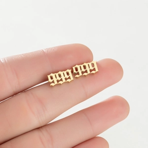 Vue macro des boucles d'oreilles dorées avec le numéro 999 en police gothique
