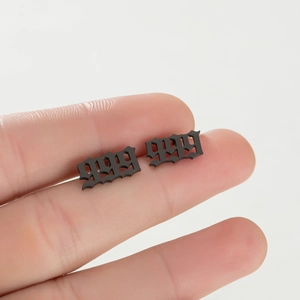 Vue macro d'une boucle d'oreille chiffre 1999 sur le bout d'un doigt montrant sa petite taille
