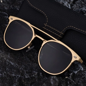 Classic gold aviator sunglasses for men with dark lenses on a black stone display base