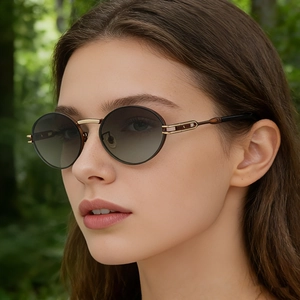 Detail of vintage oval sunglasses with gold metal temples and gradient lenses on a model