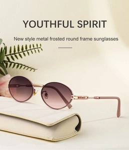 Detail of oval sunglasses with matte metal frames and gradient lenses next to leather case