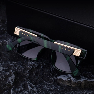Detail of green marble frame sunglasses with gold metallic accents and wide temples
