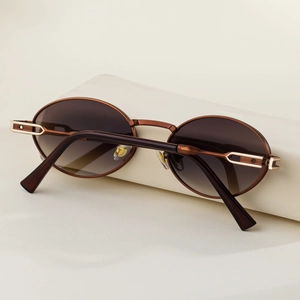 Detail of oval sunglasses featuring vintage bronze frames and hollow rectangular metal work