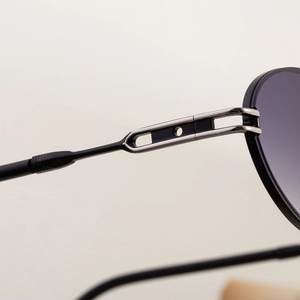 Close-up of oval sunglasses metal hinge with hollow-out design and silver rivets