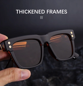 Detail of thickened black sunglasses frame with golden rivets and dark brown lenses